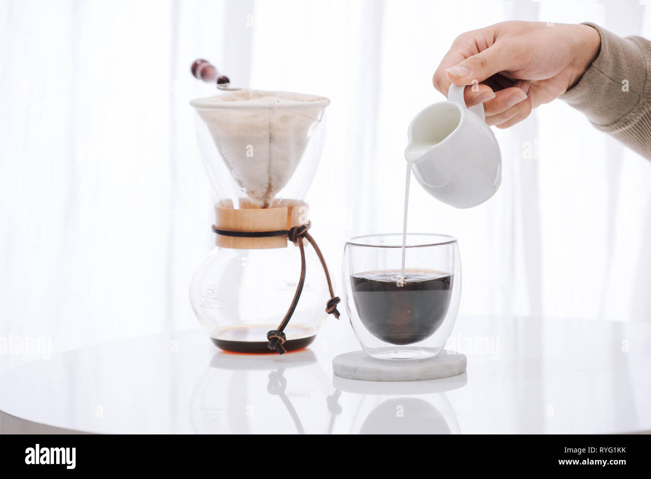 https://c8.alamy.com/comp/RYG1KK/man-pouring-milk-into-glass-with-cold-brew-coffee-on-table-RYG1KK.jpg