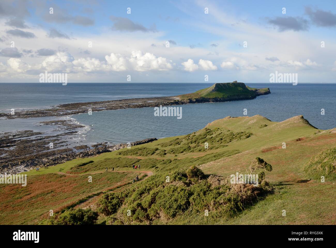 Overview of the Worm's head with a falling tide beginning to expose the tidal causeway that connects it to the mainland, Rhossili, The Gower peninsula Stock Photo
