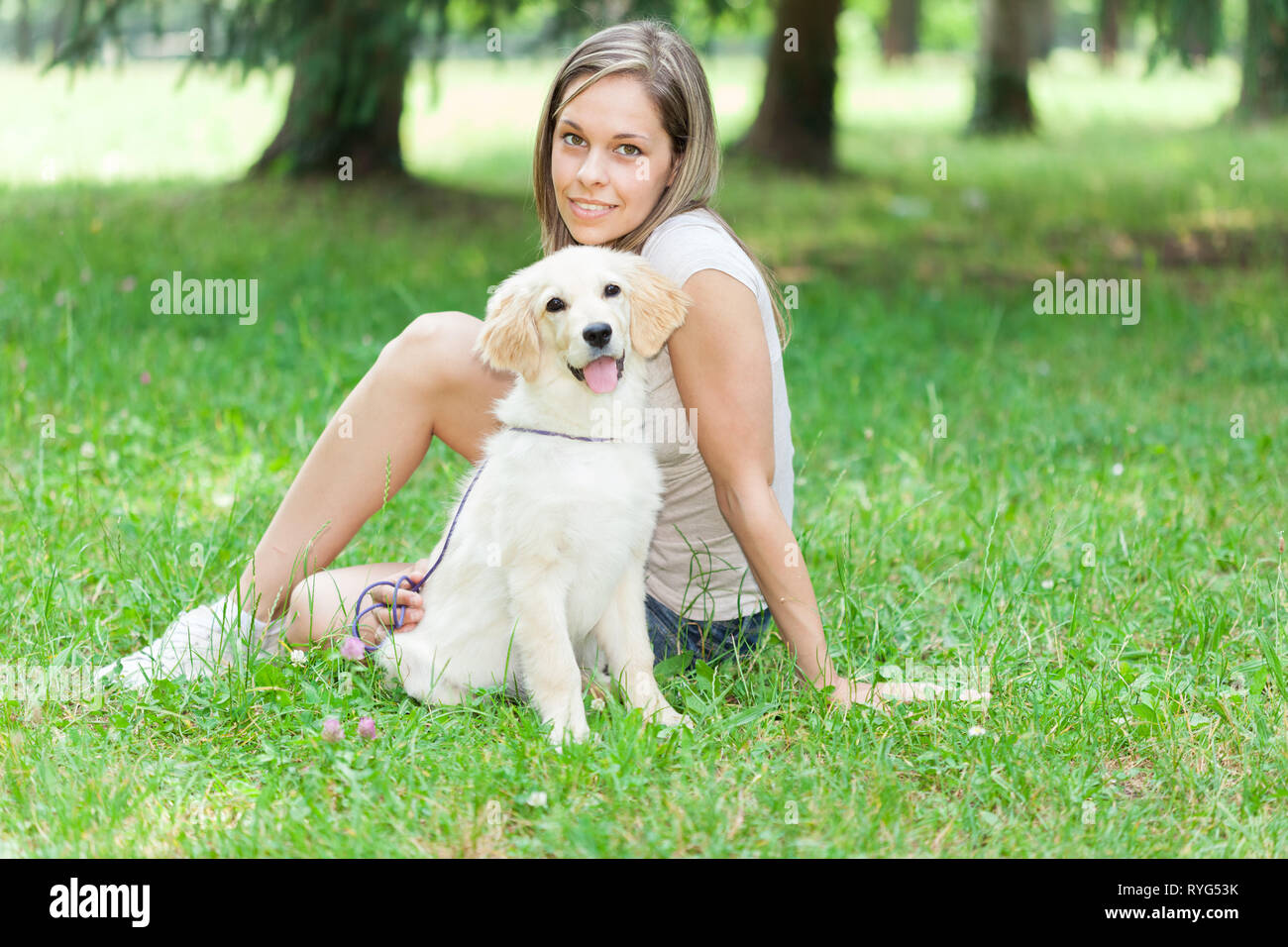 Young woman playing with her golden retriever puppy outdoors Stock ...