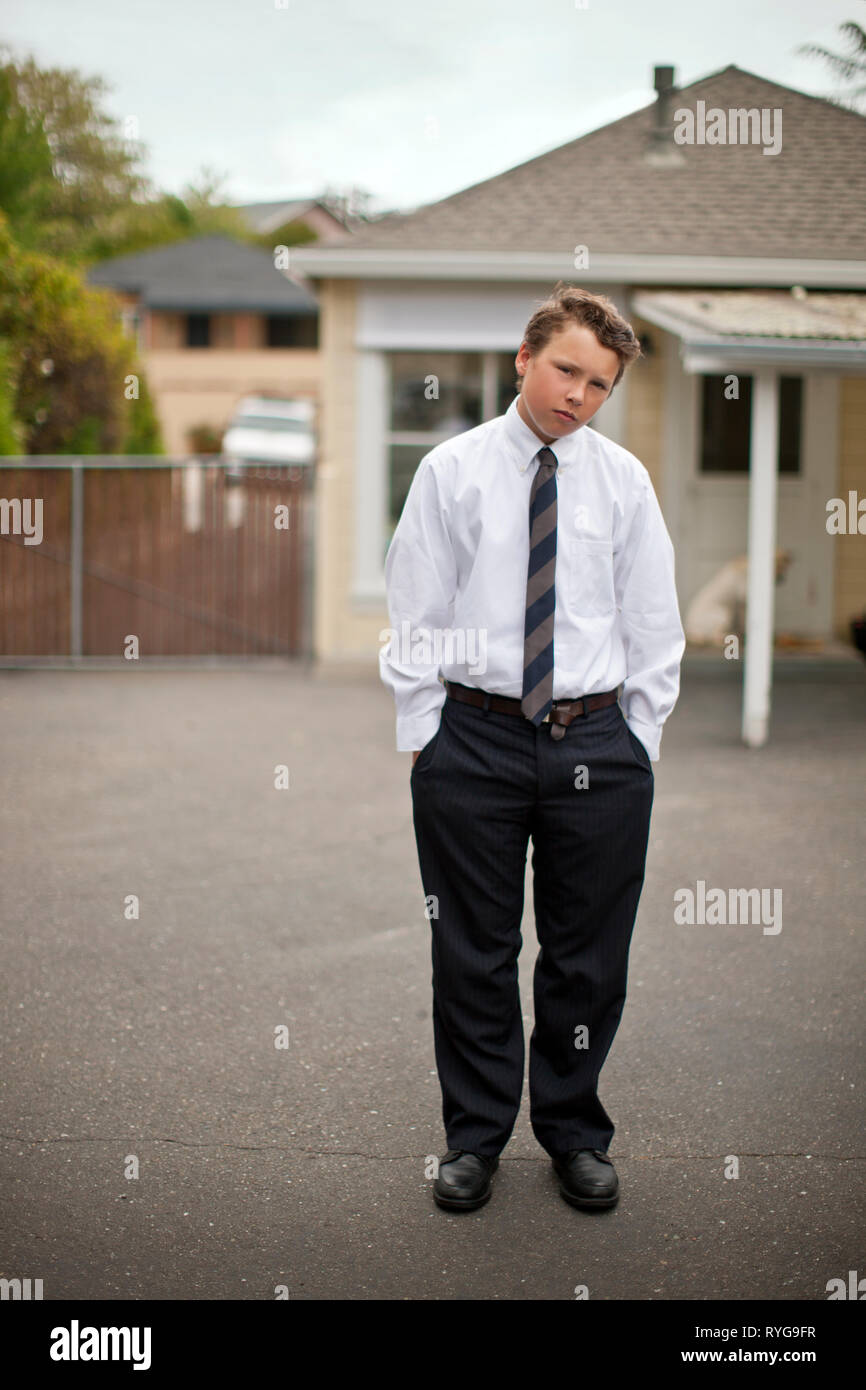 Portrait of a teenage boy dressed in a shirt and tie standing with his hands in his pockets. Stock Photo
