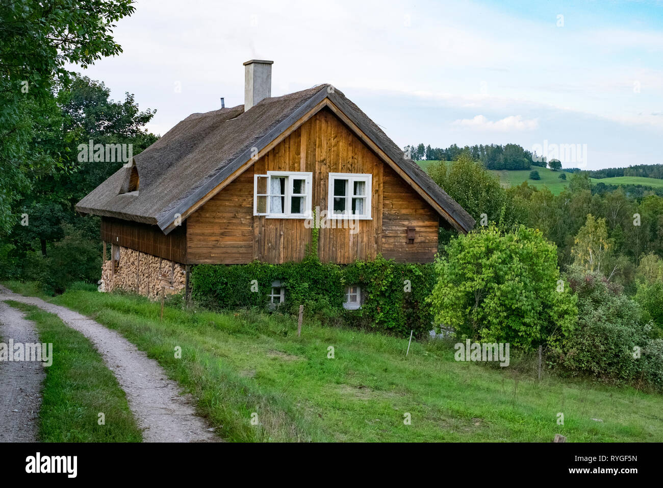 Rural wooden farm house with chimney in the hills and forest around Suwalki in northeastern Poland in the late summer. Stock Photo