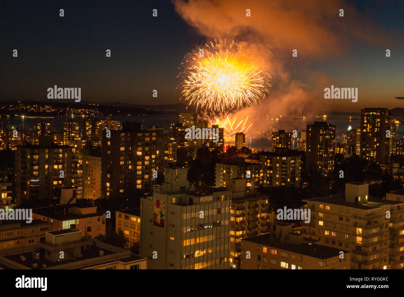 Fireworks bursting across the sky over Vancouver, British Columbia with the city skyline in the foreground. Stock Photo