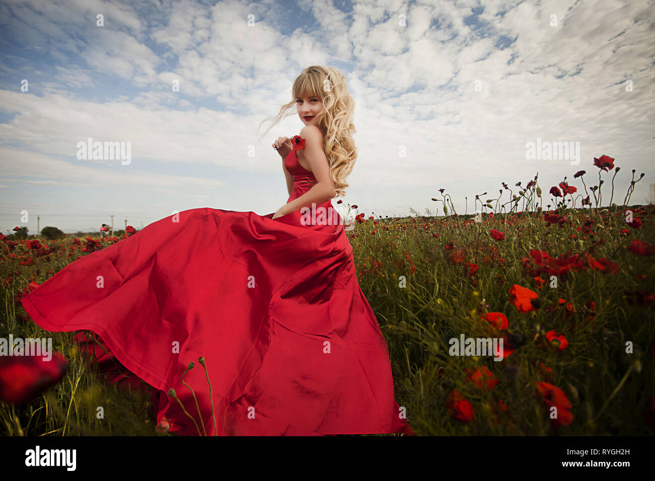 beautiful girl in a red dress walks through a field of poppies Stock ...