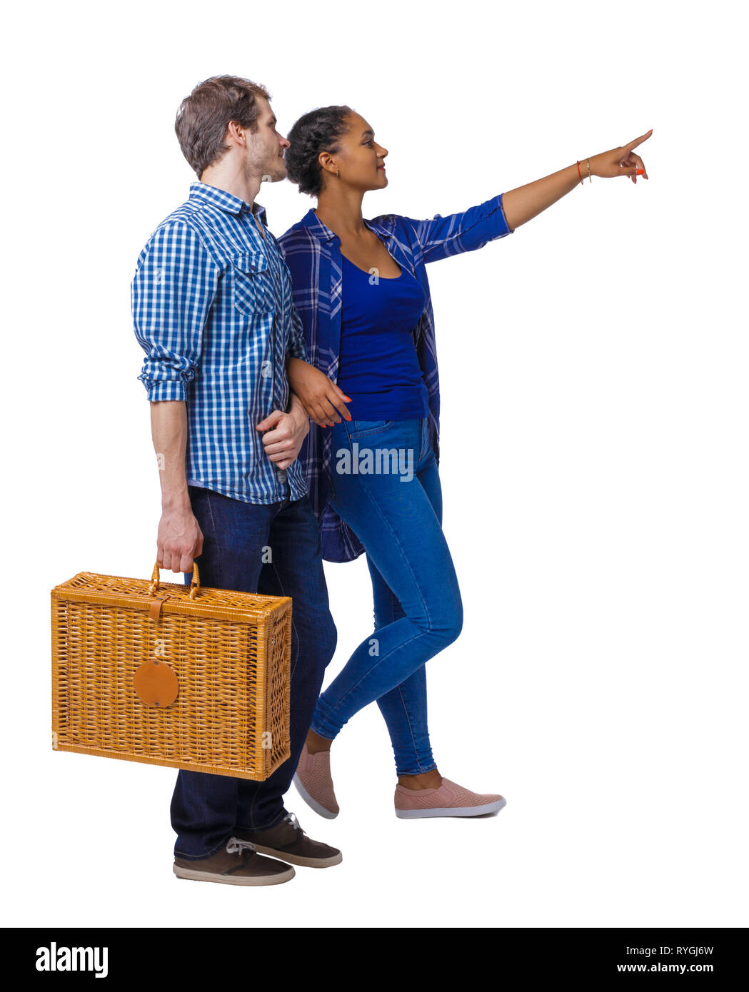 Back view of interracial going couple with a picnic bag who points somewhere. Two students go to the lecture. Rear view people collection. backside vi Stock Photo