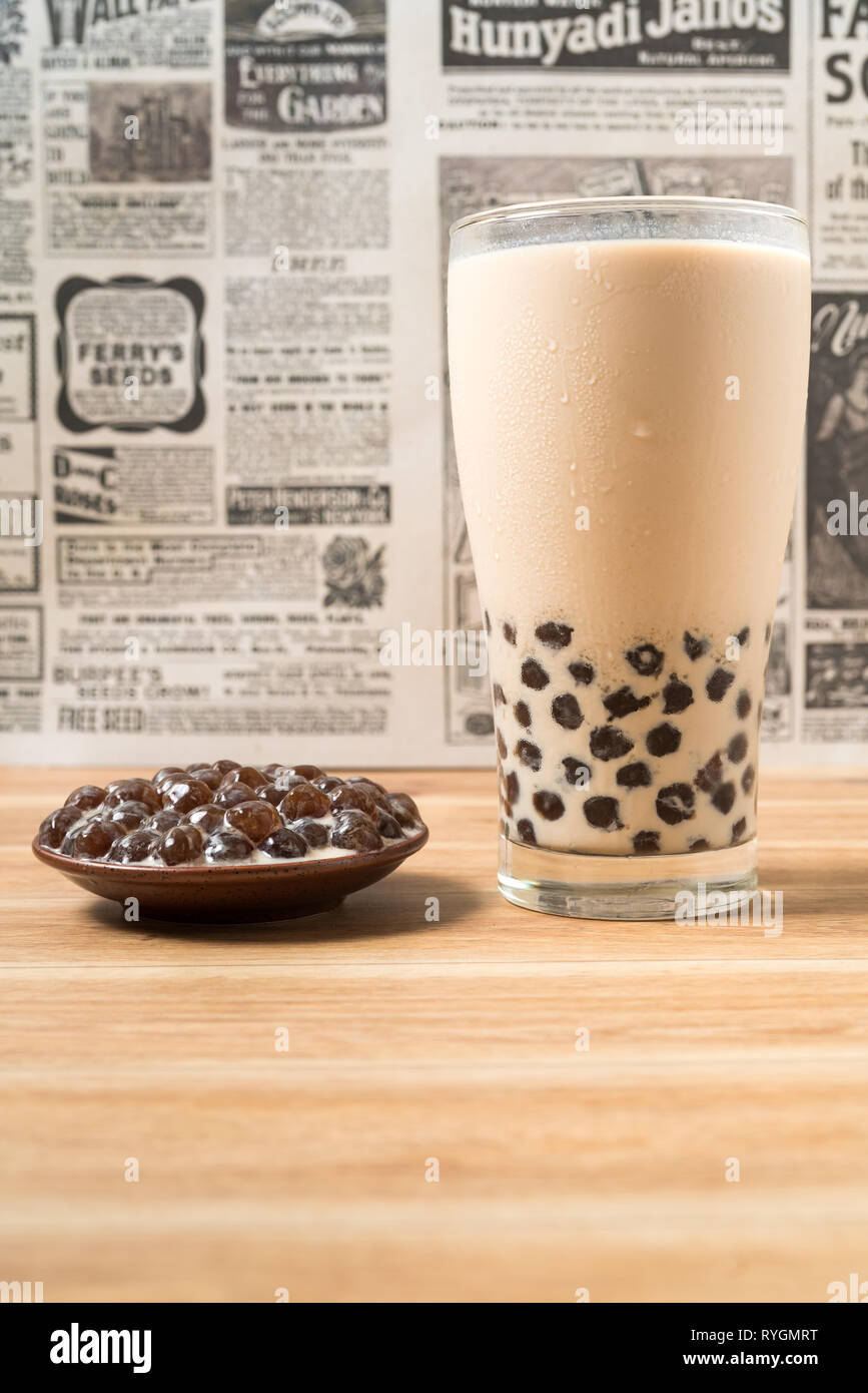 https://c8.alamy.com/comp/RYGMRT/a-glass-cup-of-pearl-milk-tea-also-called-bubble-tea-and-a-plate-of-tapioca-ball-on-wooden-background-pearl-milk-tea-is-the-most-representative-dri-RYGMRT.jpg