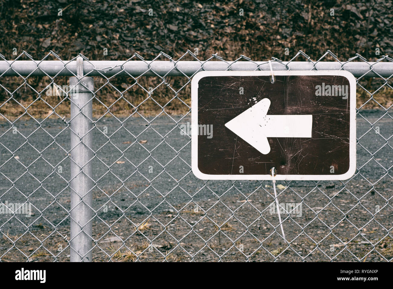 Arrow symbol direction sign on chain link fence. Stock Photo