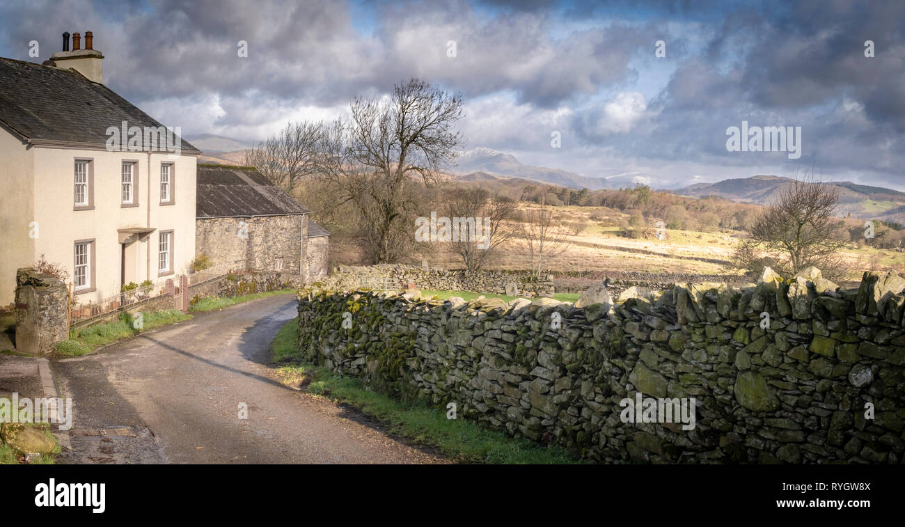 Wood Gate Farm between Gawthwaite and Lowick Green on the edge of the Lake District National Park looking up the Crake Valley towards a snow dusted Co Stock Photo