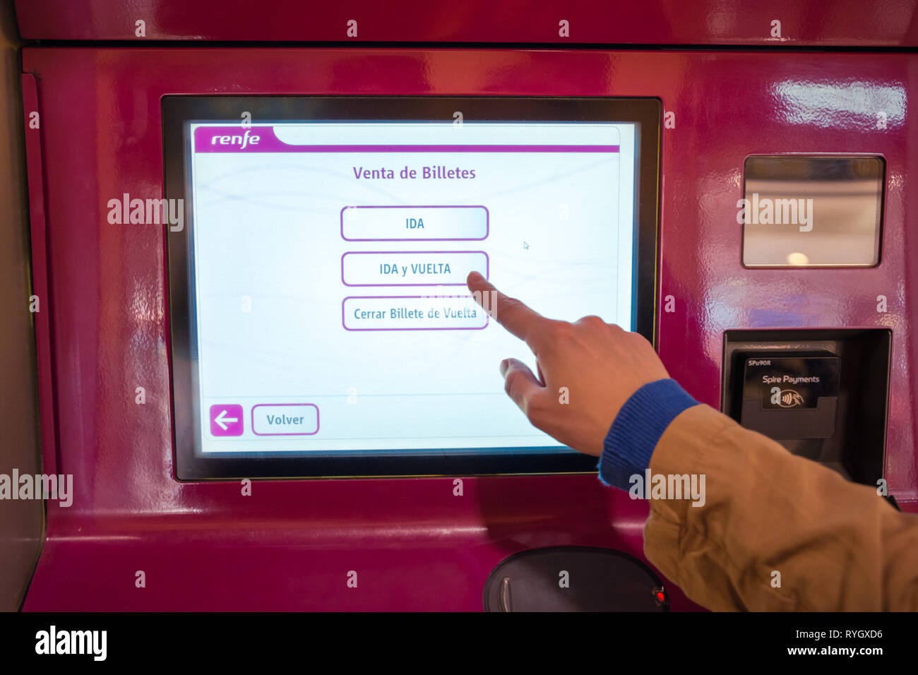 Valencia,Spain - March 09, 2019:   Finger selecting roundtrip on the touchscreen of Renfe ticket terminal. Railway ticket purchase, Spain. Stock Photo