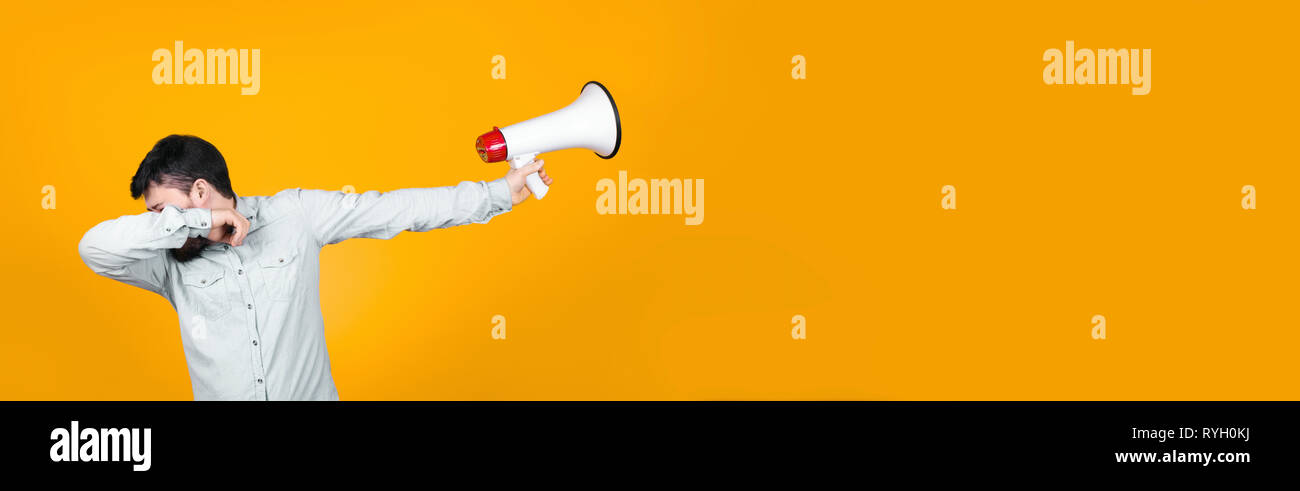 man in dub dance pose with a megaphone in his hand turns him away, concept of reluctance to protest, image on orange background Stock Photo