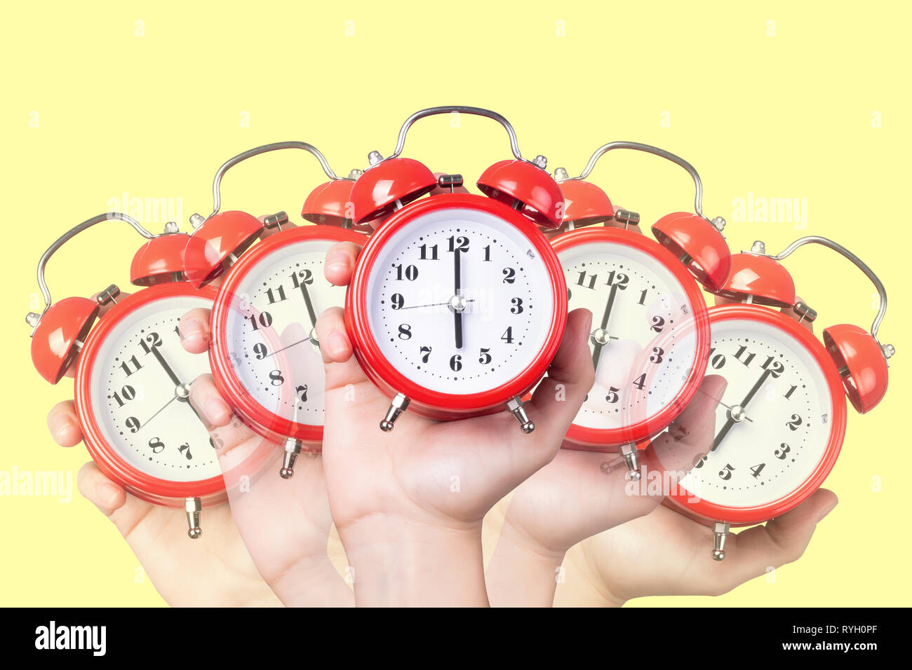 many red alarm clocks in hand, on a yellow background, concept time to