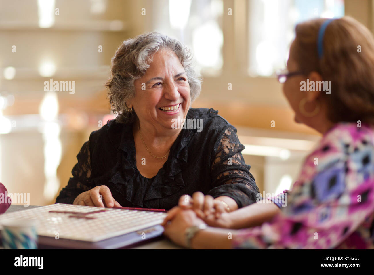 Two happy senior women playing a board game together at a table. Stock Photo