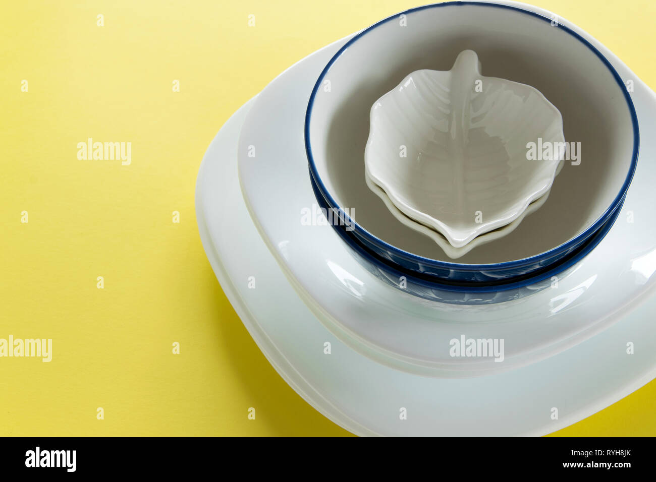 Different porcelain tableware on fresh yellow background Stock Photo ...