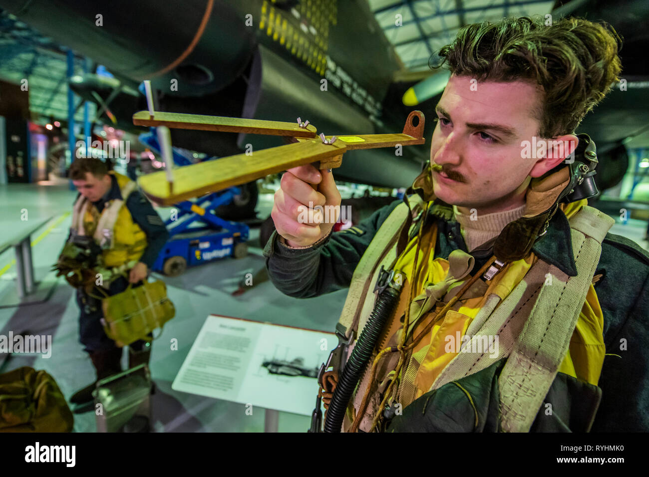 London, UK. 14th March, 2019. A re-enactor with a replica of the Dambuster aiming device in front of the Lancaster - Immersive Histories: Dambusters Virtual Reality Experience. An opportunity to step back in time to the early hours of 17 May 1943 and on board Avro Lancaster G-George to join the Dambusters on their legendary mission. Using the latest virtual reality and haptic technology, in conjunction with a physical 1:1 recreation of the interior of the iconic Avro Lancaster bomber. Credit: Guy Bell/Alamy Live News Credit: Guy Bell/Alamy Live News Stock Photo