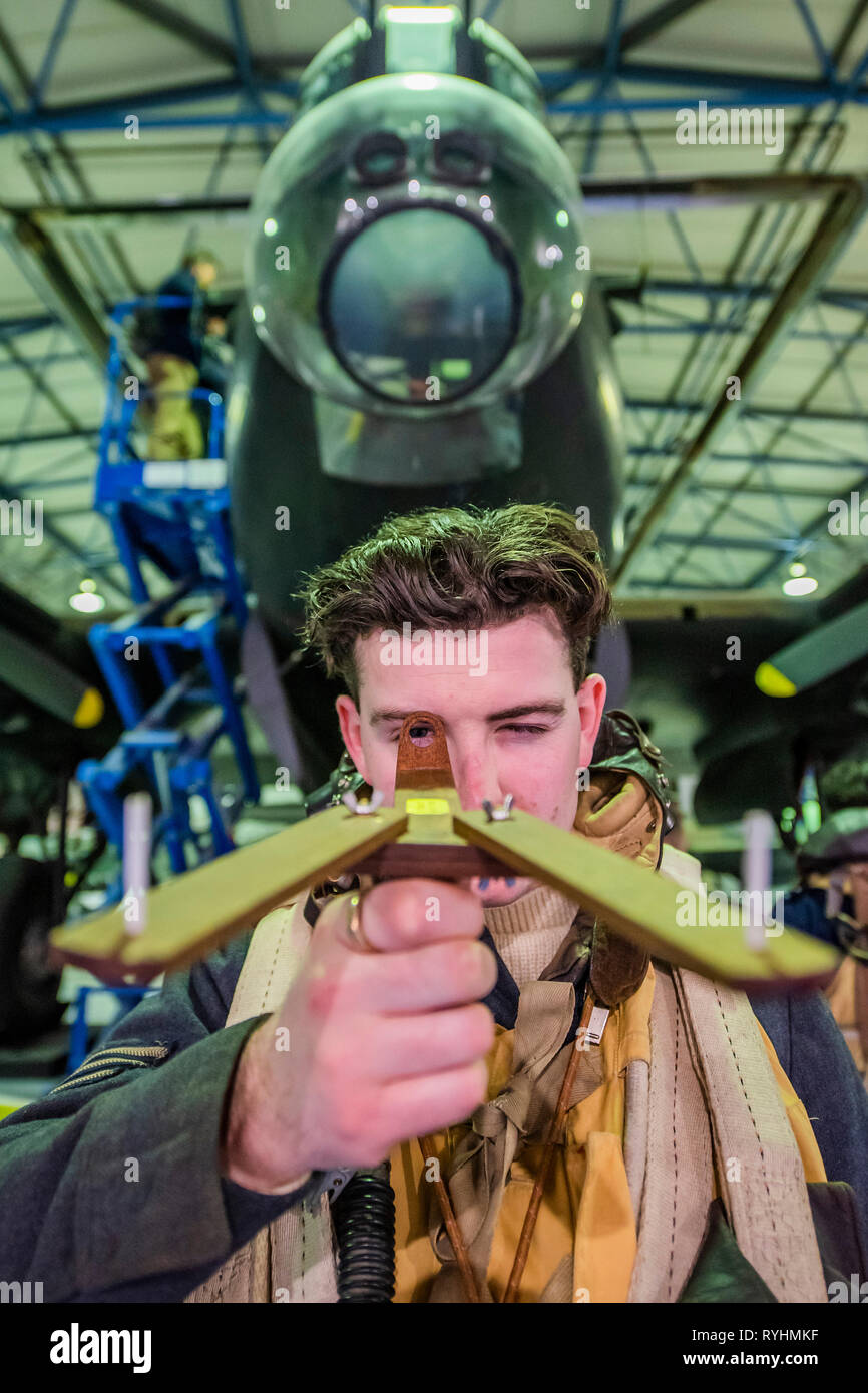 London, UK. 14th March, 2019. A re-enactor with a replica of the Dambuster aiming device in front of the Lancaster - Immersive Histories: Dambusters Virtual Reality Experience. An opportunity to step back in time to the early hours of 17 May 1943 and on board Avro Lancaster G-George to join the Dambusters on their legendary mission. Using the latest virtual reality and haptic technology, in conjunction with a physical 1:1 recreation of the interior of the iconic Avro Lancaster bomber. Credit: Guy Bell/Alamy Live News Credit: Guy Bell/Alamy Live News Stock Photo