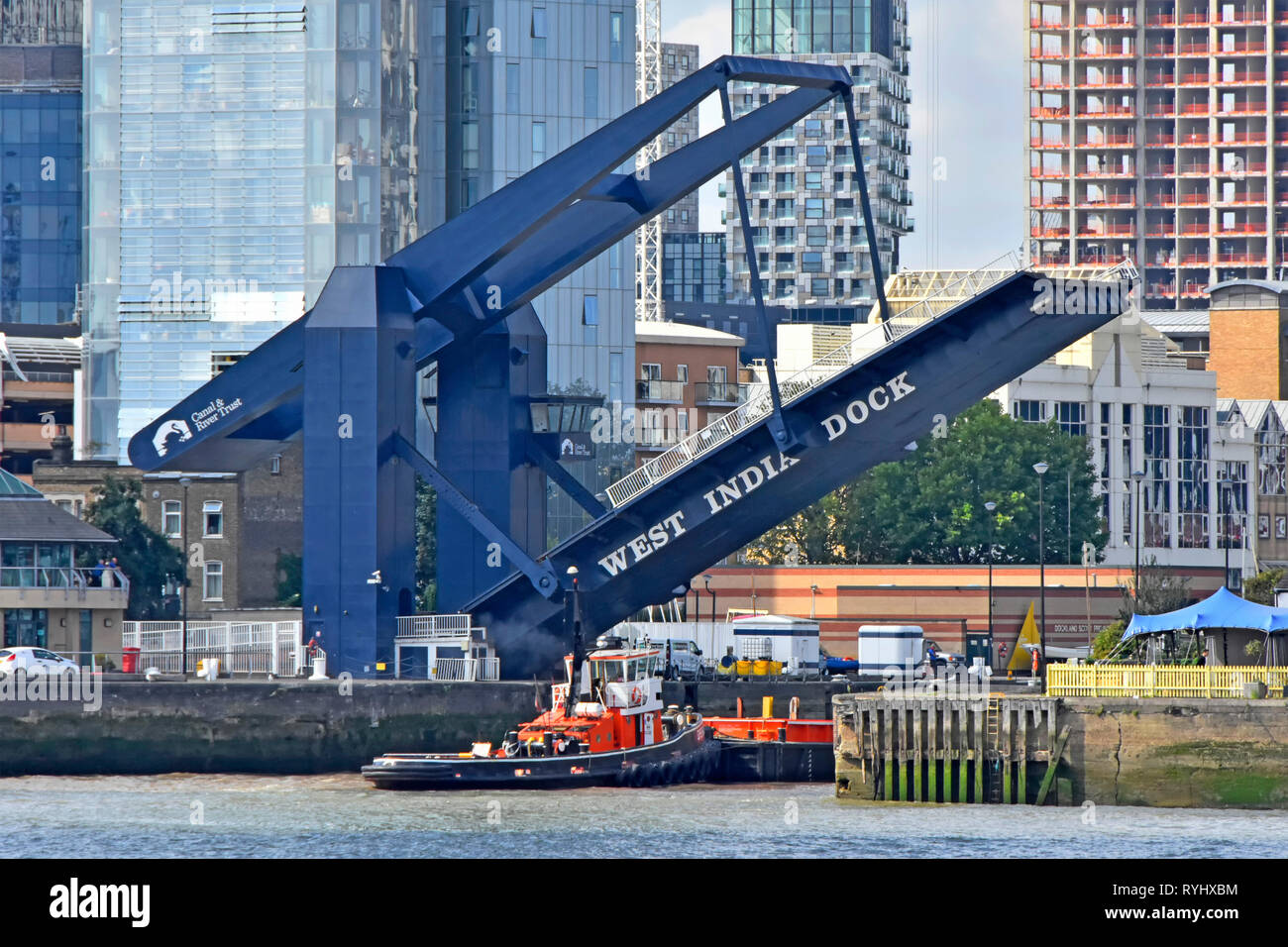 River Thames & raised modern road bridge entrance for tug boat into South Dock of West India Docks access to Canary Wharf estate London Docklands UK Stock Photo