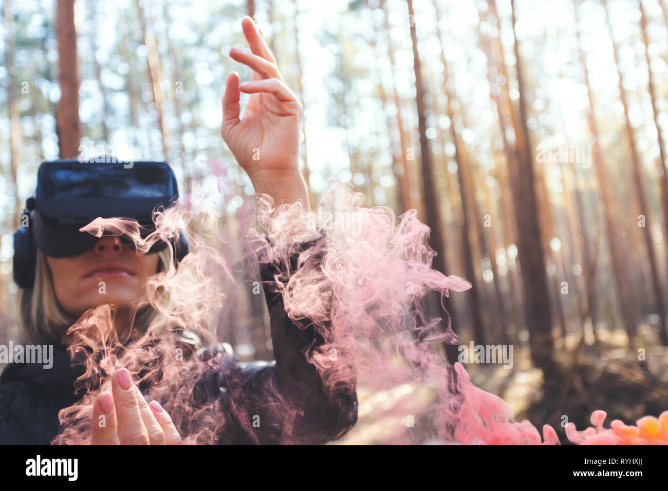 A woman wearing virtual reality goggles in the forest sees smoke bombs