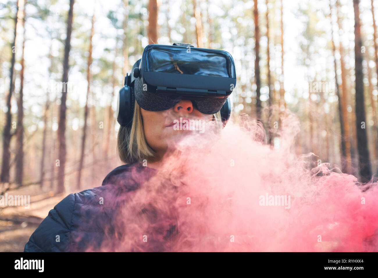 A woman wearing virtual reality goggles in the forest sees smoke bombs. VR  glasses Stock Photo - Alamy