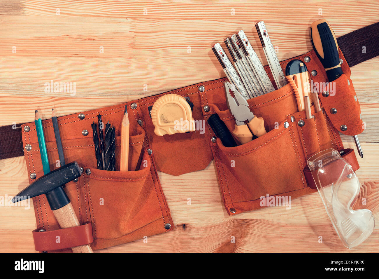 Organized handyman tool belt on work desk Stock Photo