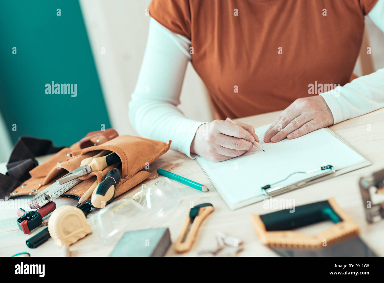Self employed female carpenter writing project notes on clipboard note paper, selective focus Stock Photo