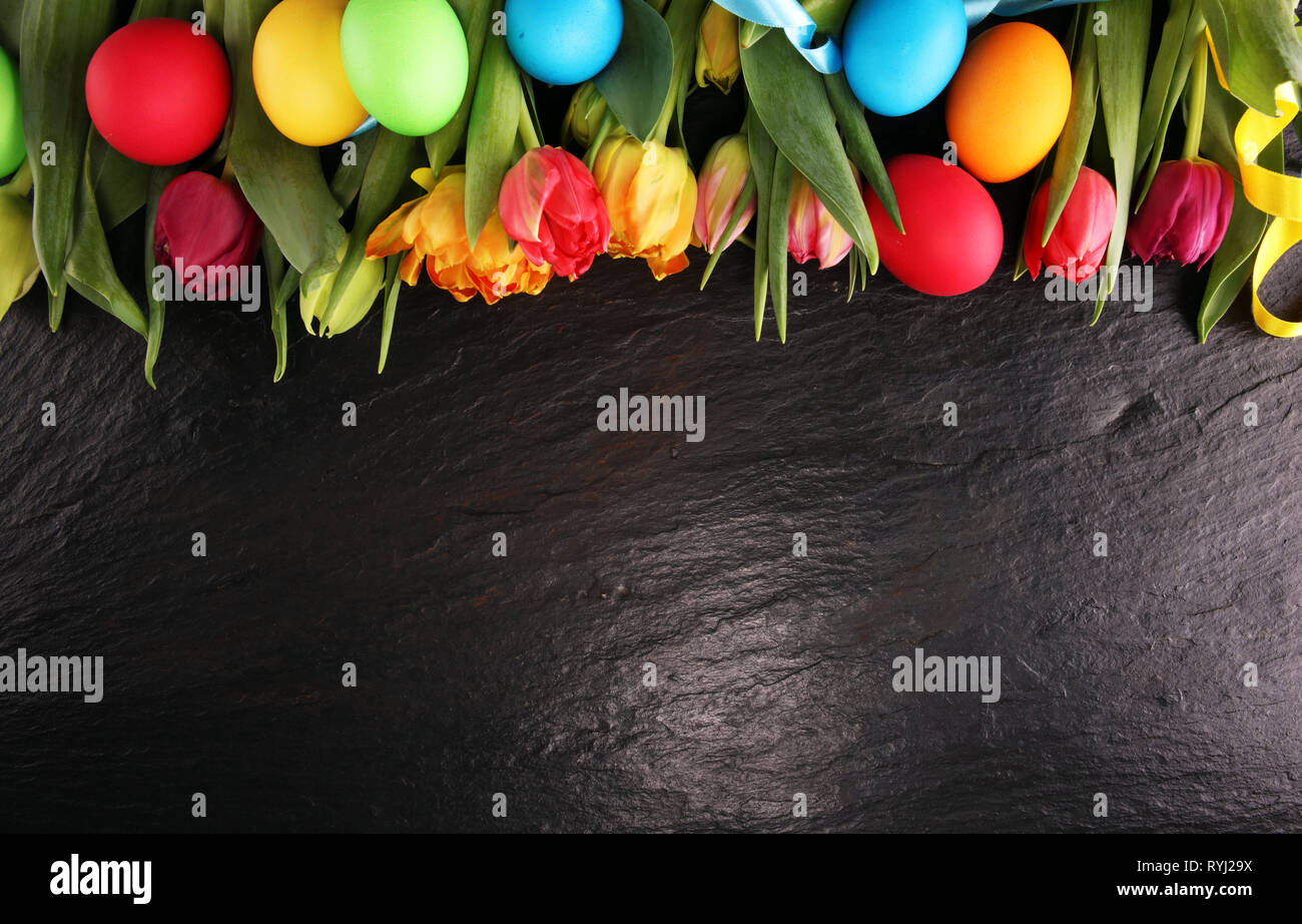 Easter eggs and colorful tulips on rustic table Stock Photo