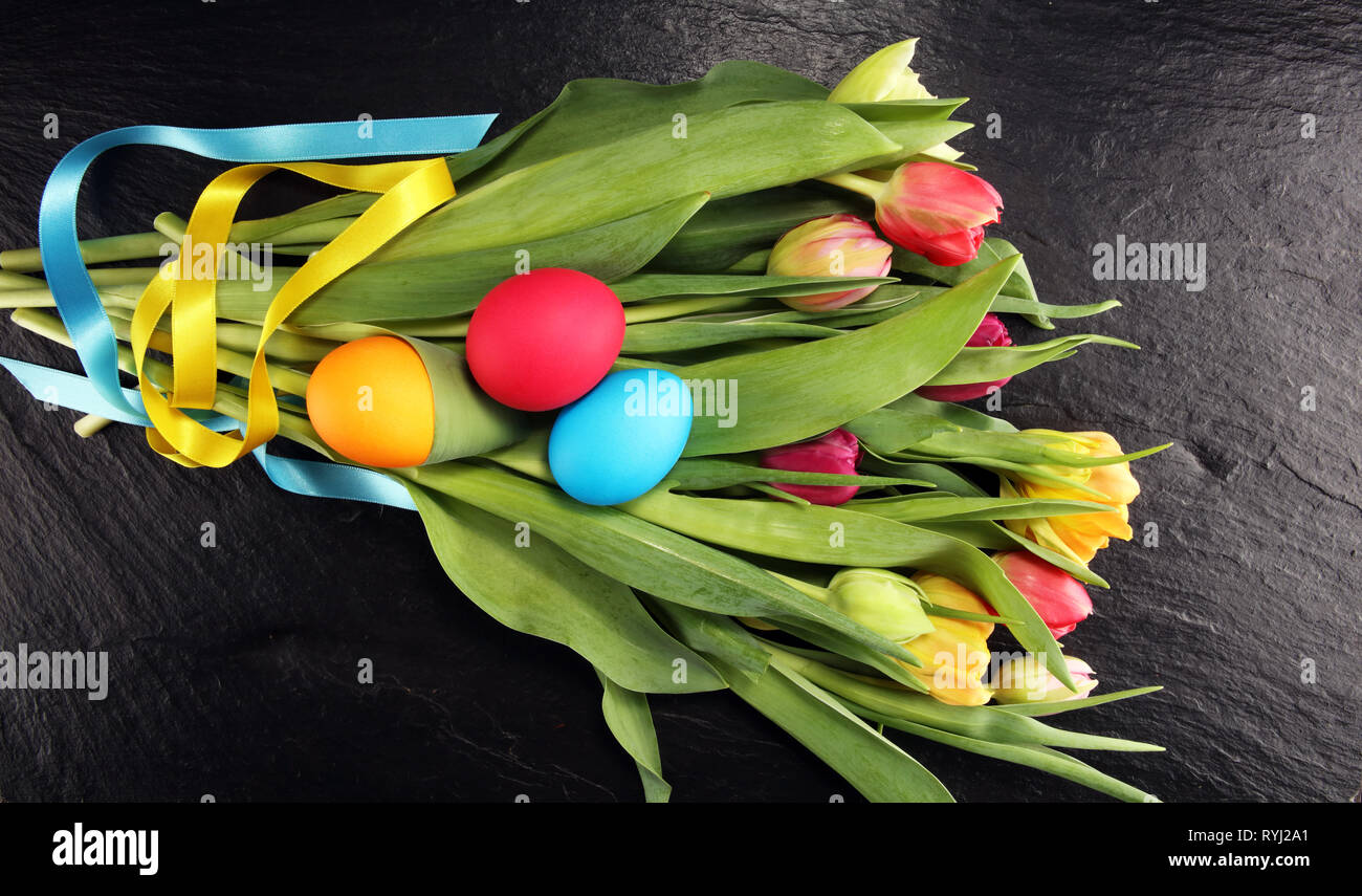 Easter eggs and colorful tulips on rustic table Stock Photo - Alamy
