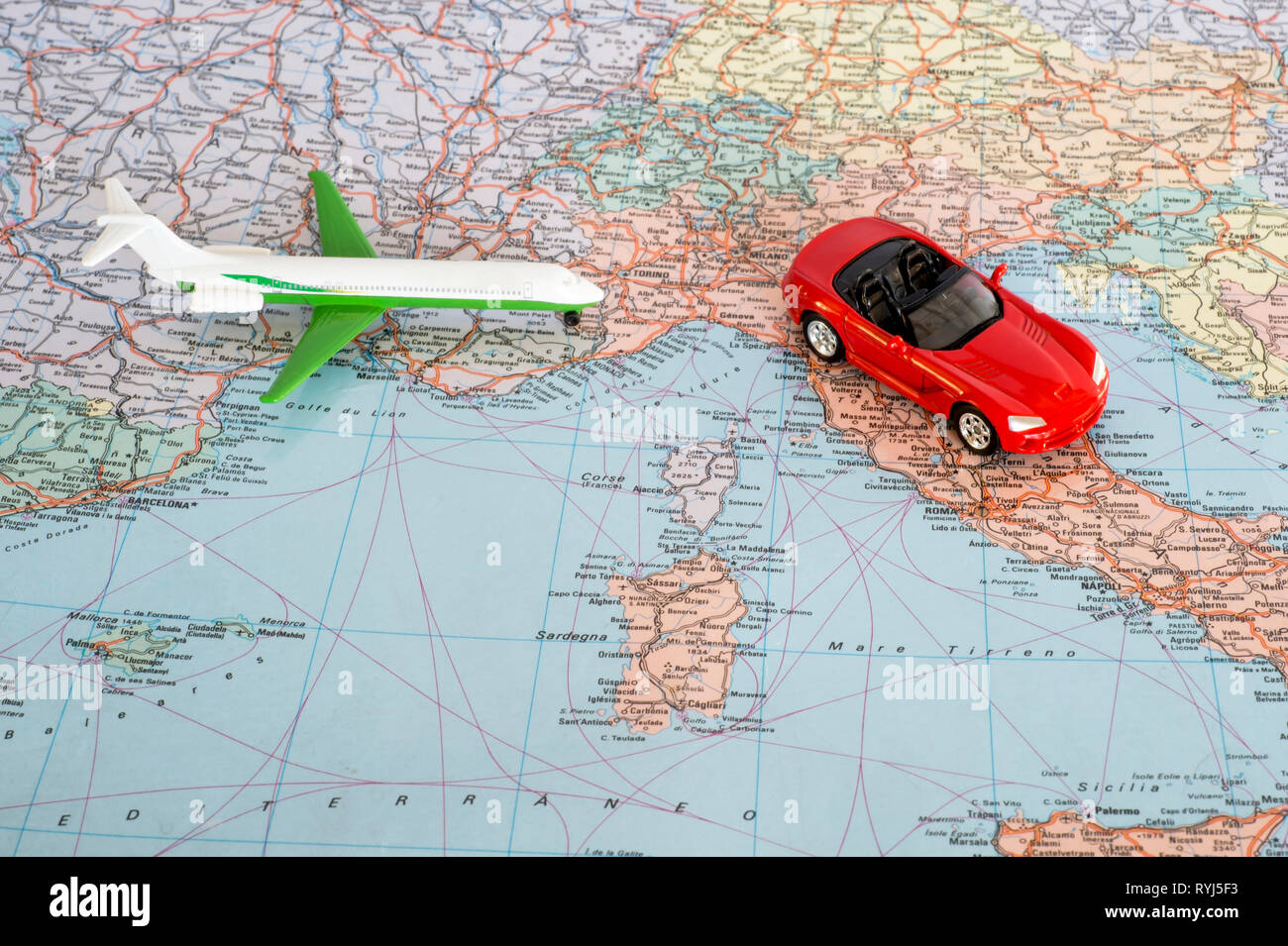 Toy plane and red car on the geographical map of Europe. Travel route