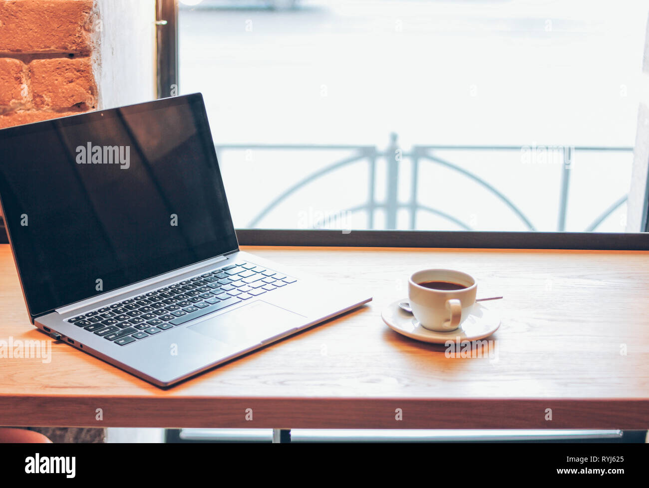 Open Laptop And A Cup Of Coffee On The Table In The Cafe
