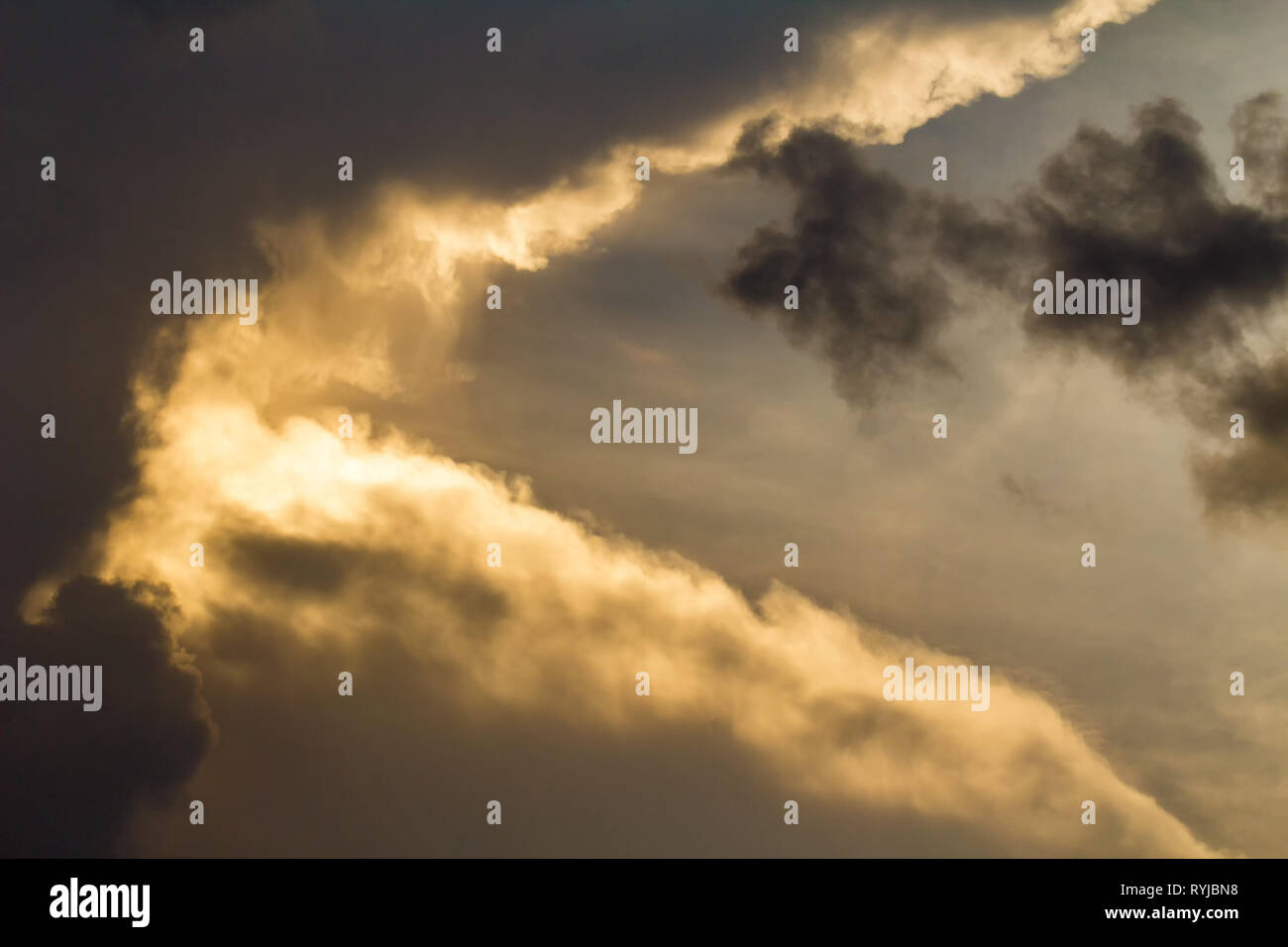 Dark clouds with orange sunset light on sky Stock Photo