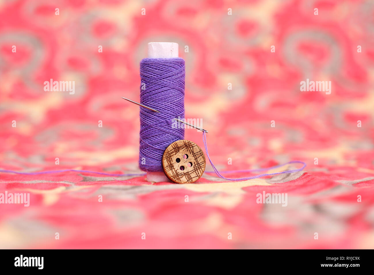 Portrait of purple sewing thread, needle and button. Isolated on the