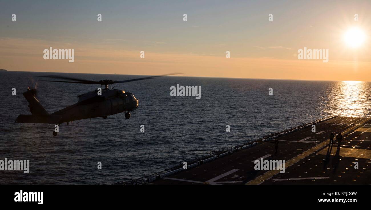 190312-N-KO533-0025  ATLANTIC OCEAN (Mar. 12, 2019) An MH-60S Sea Hawk, assigned to the Chargers, of the Helicopter Sea Combat Squadron (HSC) 26, lands on the flight deck during night operations aboard the amphibious assault ship USS Bataan (LHD 5). The ship is underway conducting sea trials. (U.S. Navy photo by Mass Communication Specialist 3rd Class Lenny Weston). Stock Photo