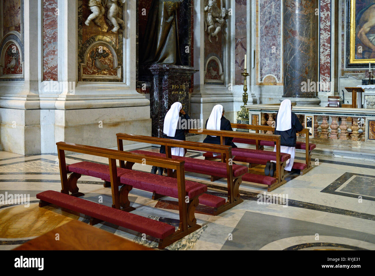 Three Nuns Praying in Saint Peter's Basilica, Church or Cathedral, Vatican, Rome, Italy Stock Photo