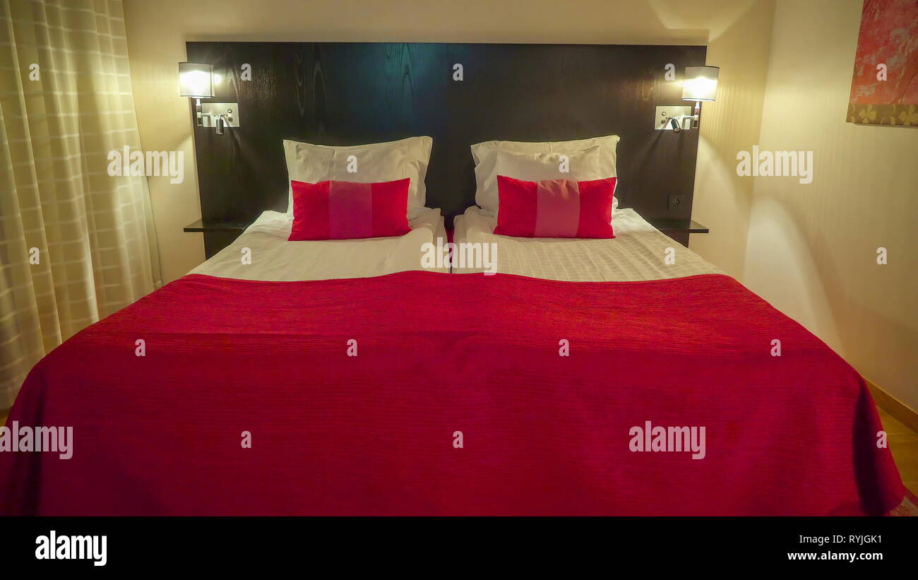 The Clean Red And White Sheet Of The Bed Inside The Bedroom