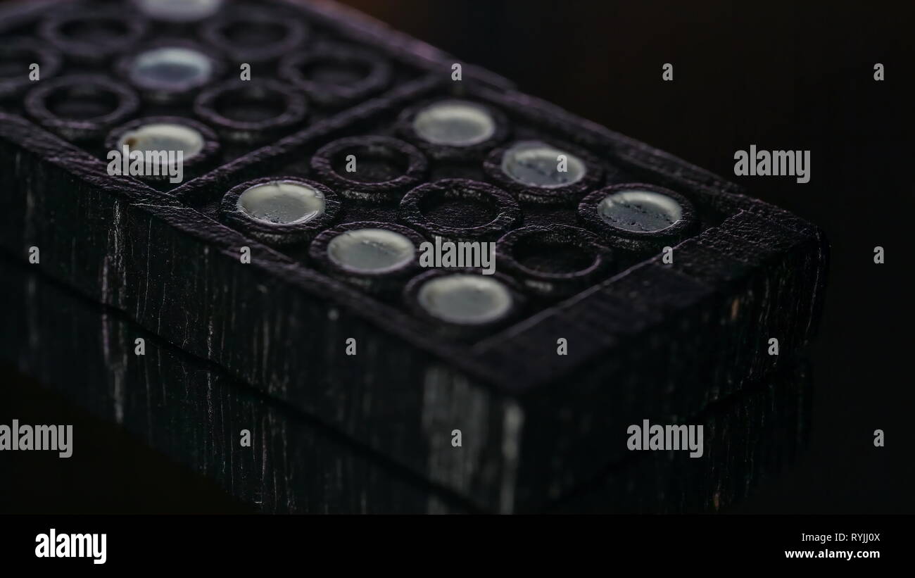 The black top of the dominoes on a macro shot with the black and white holes on it Stock Photo
