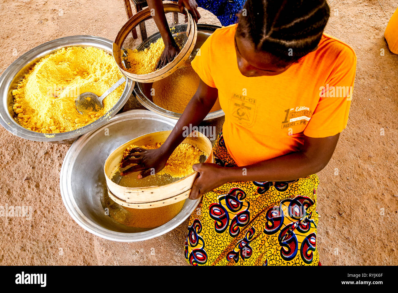 Girl making flour in Koudougou, Burkina Faso. Stock Photo
