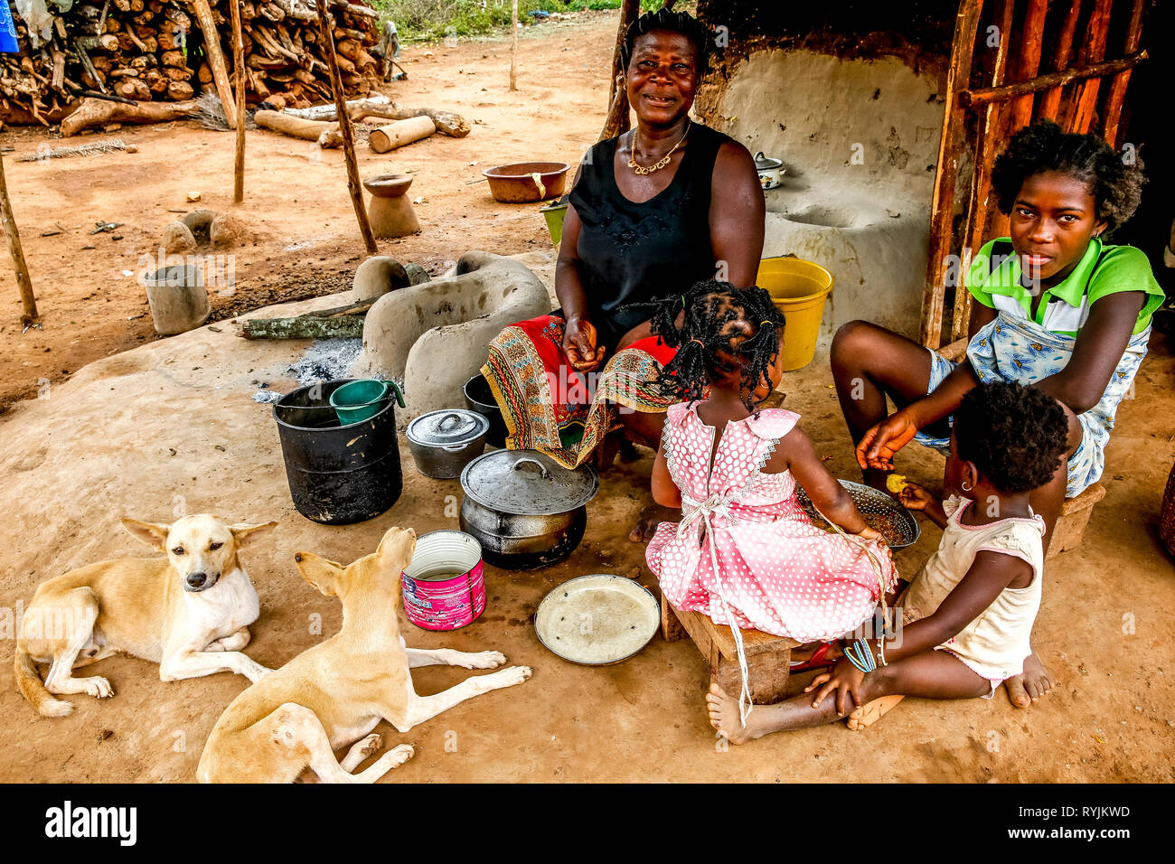 Mother and children sitting in the kitchen area outside their home in a village near Daloa, Ivory Coast. Stock Photo