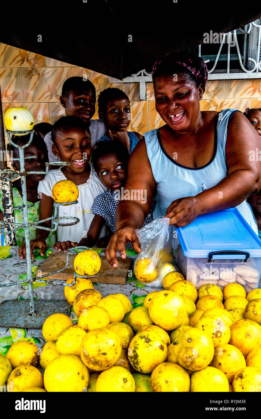 Woman surrounded with children selling fruit in Abidjan, Ivory Coast. Stock Photo