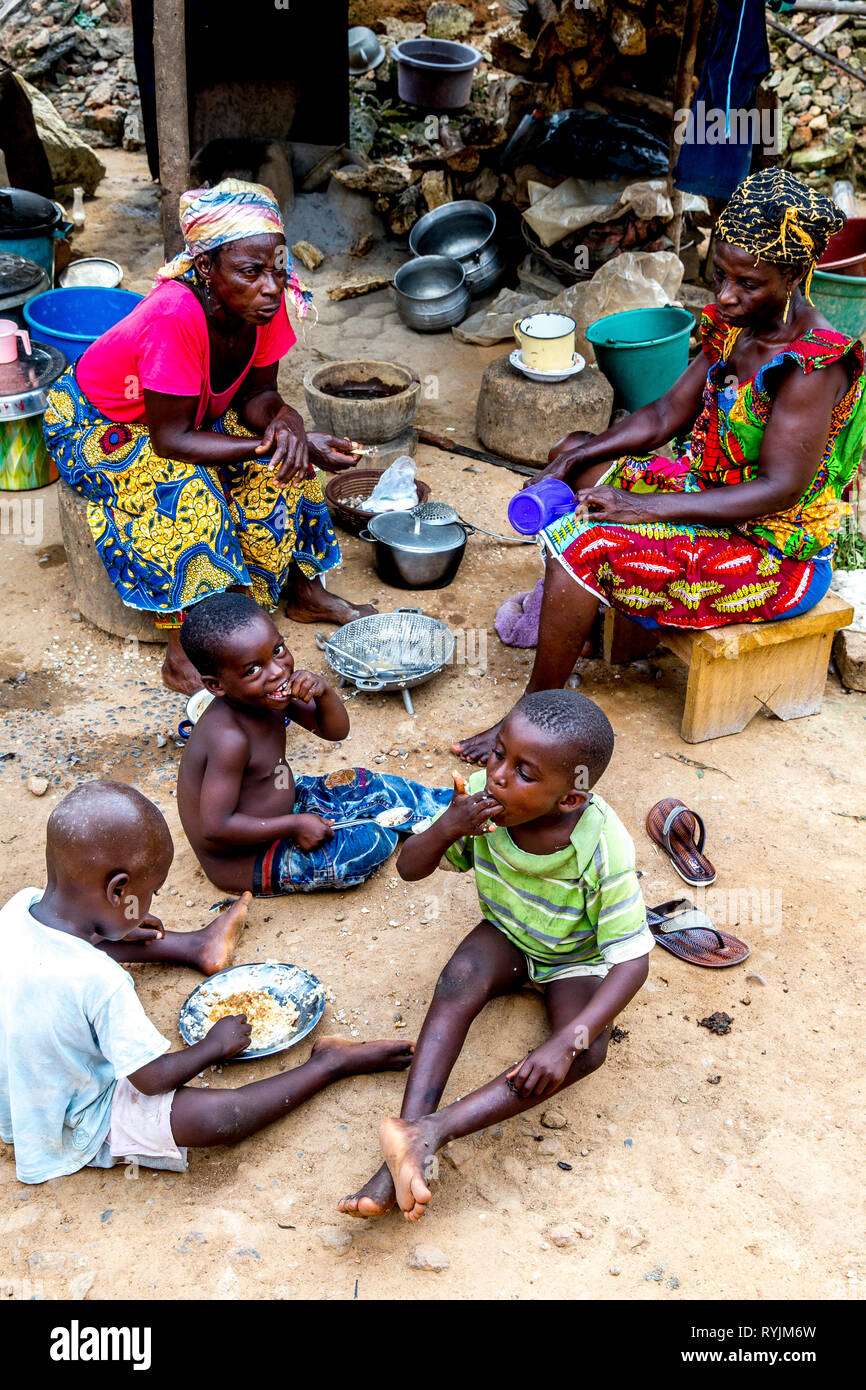 Village women and children sitting outside their home near Agboville, Ivory Coast. Stock Photo