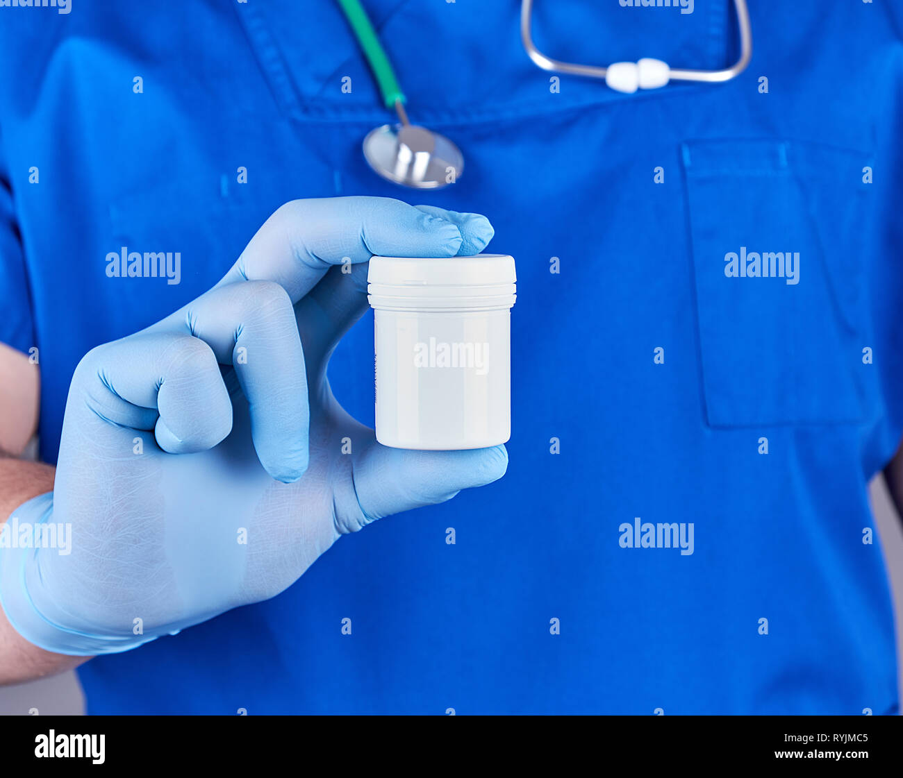 doctor in blue uniform and sterile latex gloves holds plastic pill packaging, selective focus Stock Photo