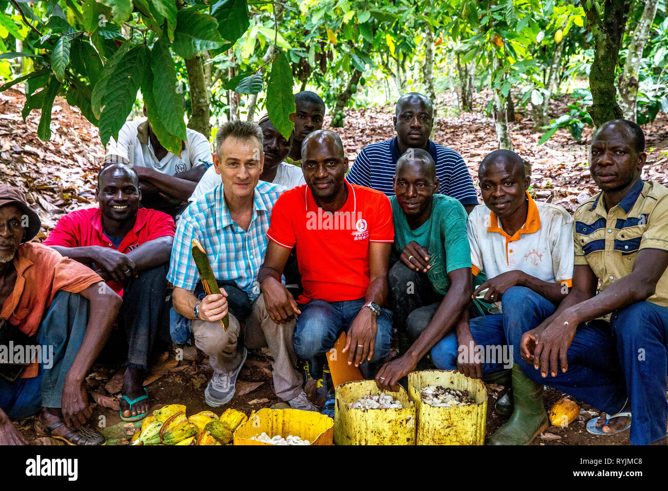 Photographer sitting with cocoa planters in Guezon, ivory Coast. Stock Photo