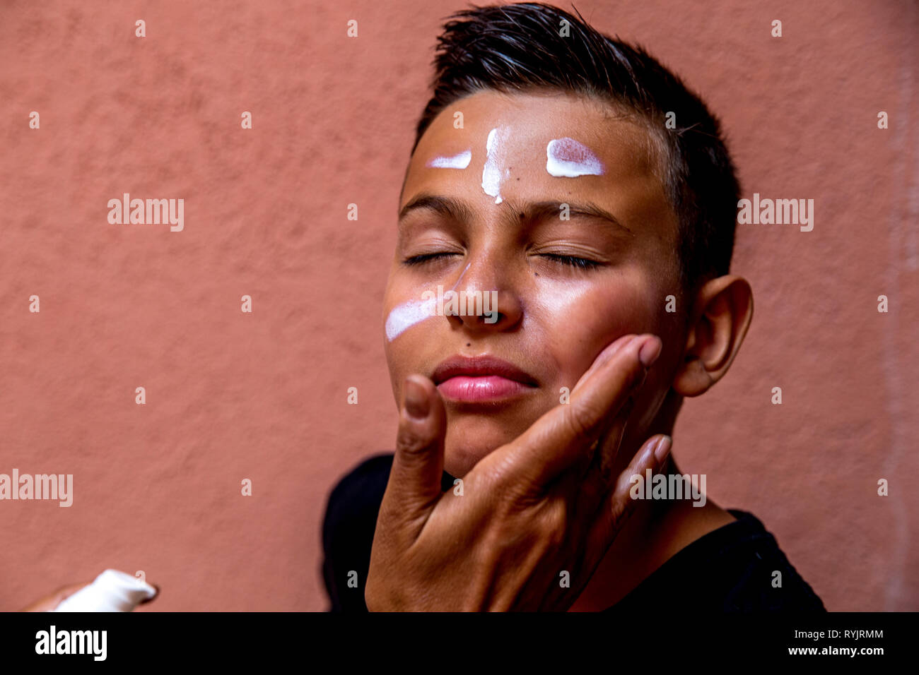 Woman applying sun cream on a 12-year-old boy in Catania, Sicily (Italy). Stock Photo