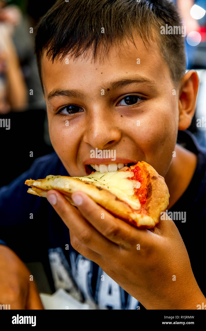 12-year-old boy eating pizza in Catania, Sicily (Italy). Stock Photo