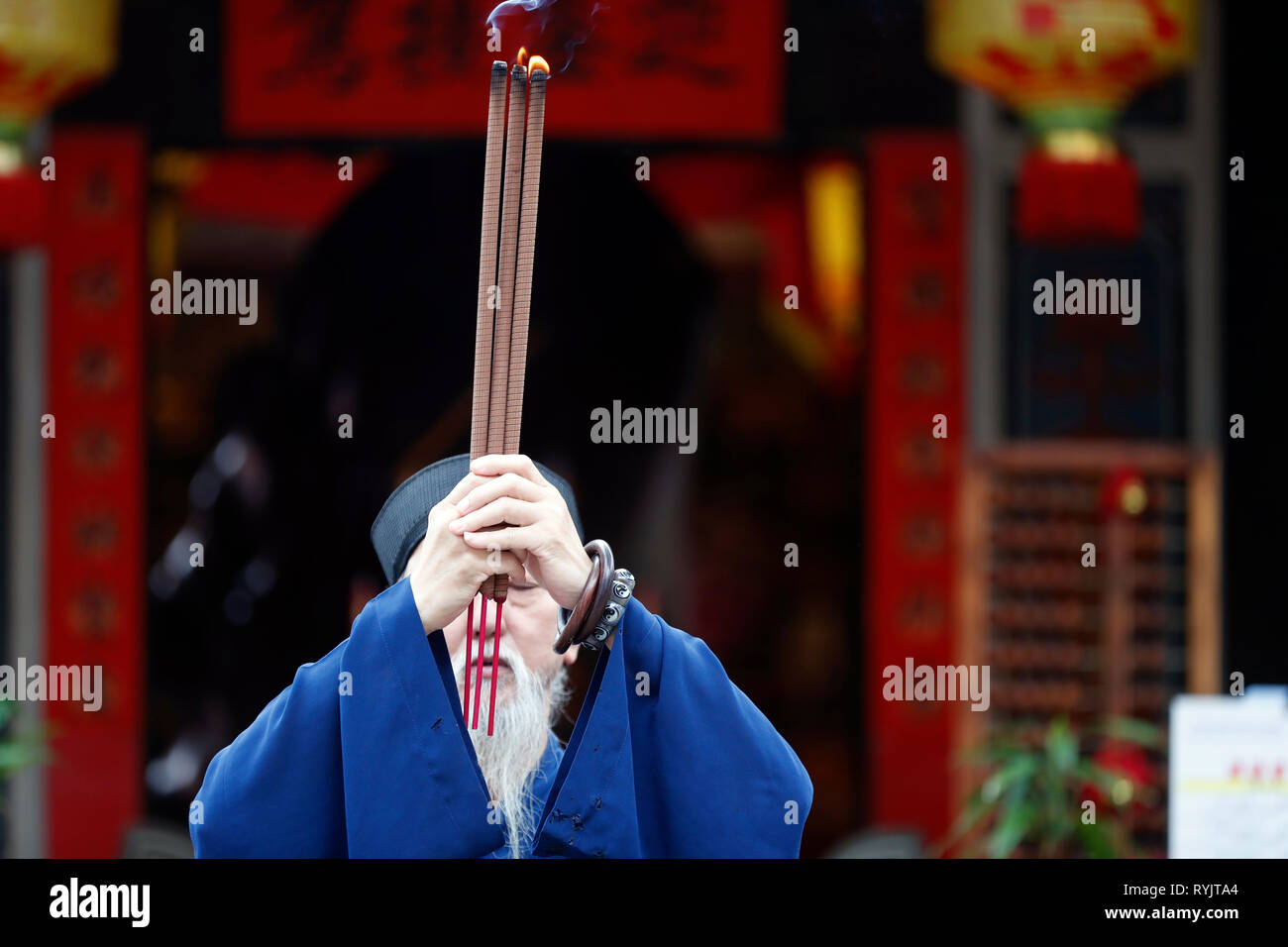 Taoist Mission. Old priest praying with 3 incense sticks.  Singapore. Stock Photo
