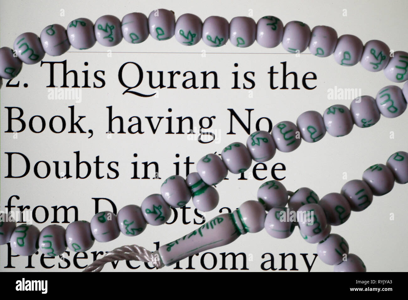 Digital Quran on a smartphone and muslim prayer beads.  English translation.  Close-up. Stock Photo