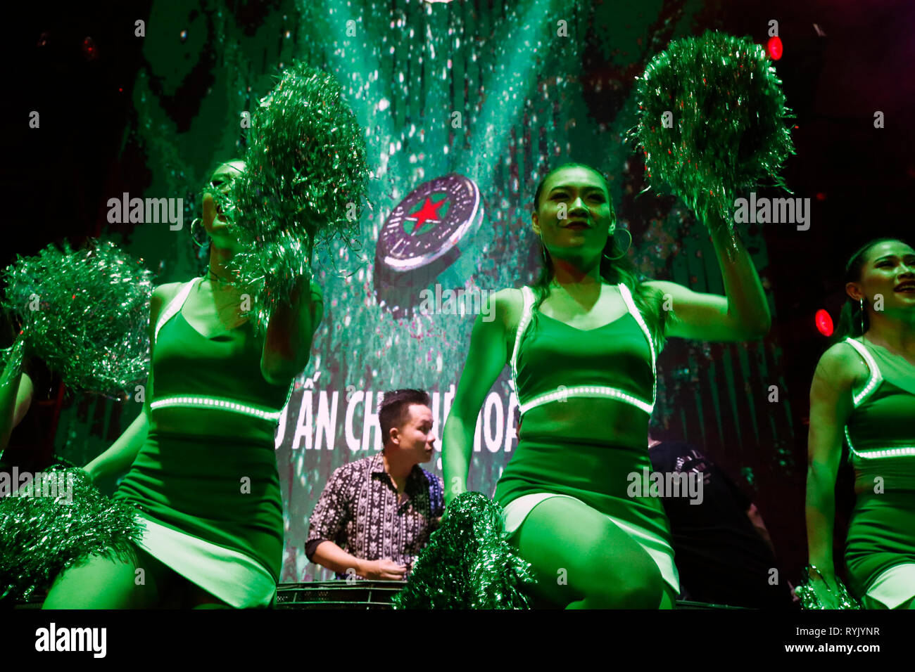 DJ on stage and Heineken girls gesturing to crowd dancing in nightclub.  Ho Chi Minh City. Vietnam. Stock Photo