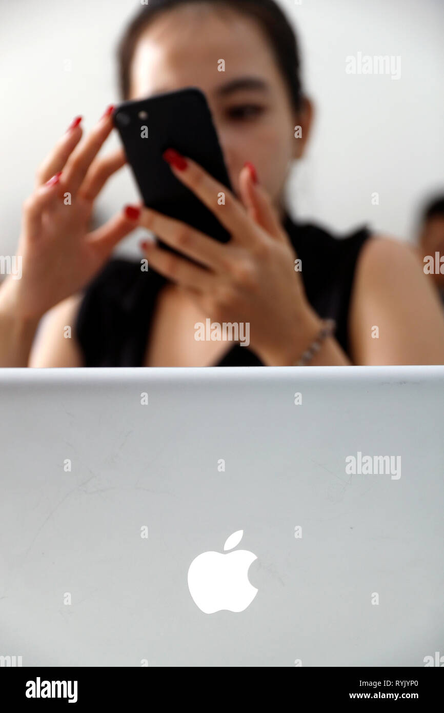 Woman with smartphone and laptop. Iphone and Mac Book.  Ho Chi Minh City. Vietnam. Stock Photo