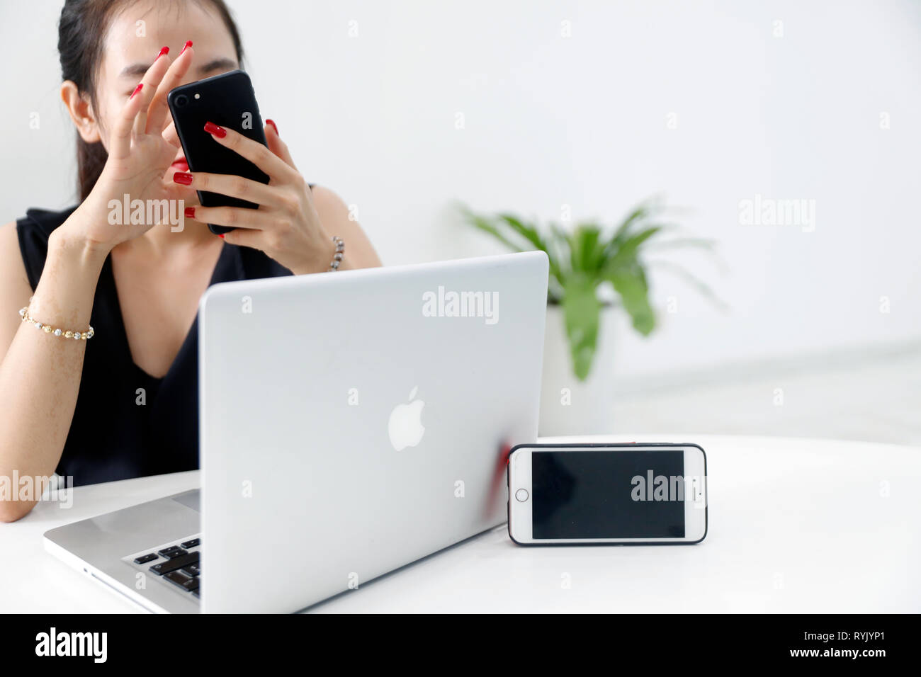 Woman with smartphone and laptop. Iphone and Mac Book.  Ho Chi Minh City. Vietnam. Stock Photo