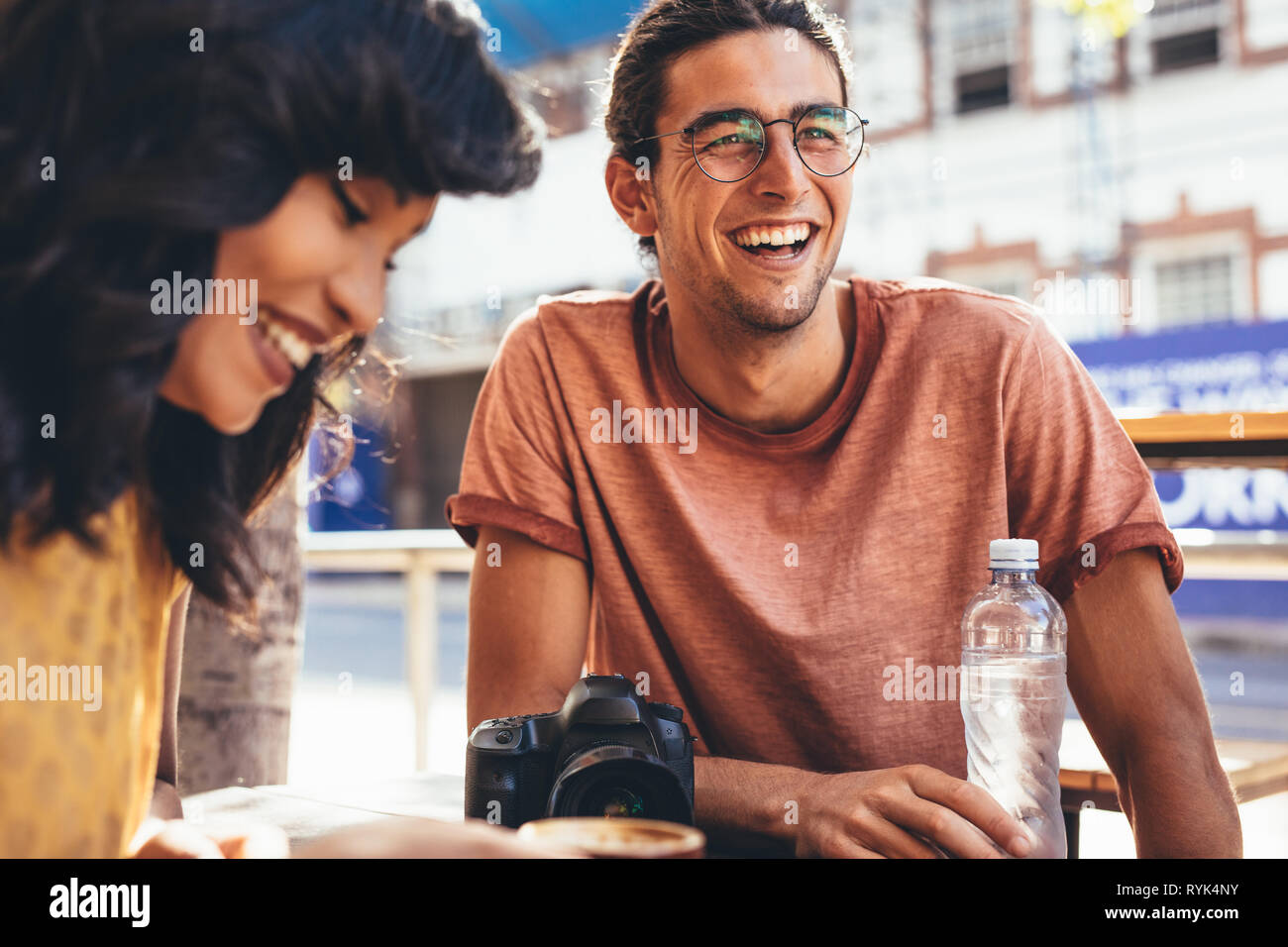 Smiling young man talking with friends at cafe. Creative people meeting at city cafe. Stock Photo