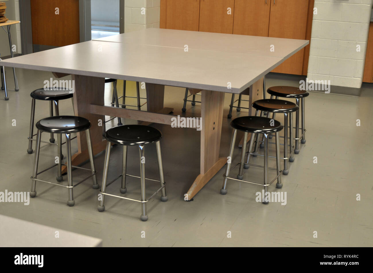 A Large Table with Stools all around on the Interior of an Art Classroom Stock Photo