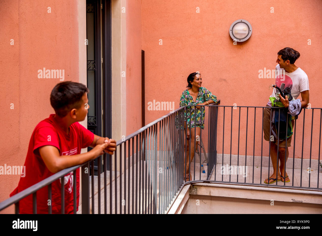 Child and adults on a balcony in Catania, Sicily (Italy). Stock Photo