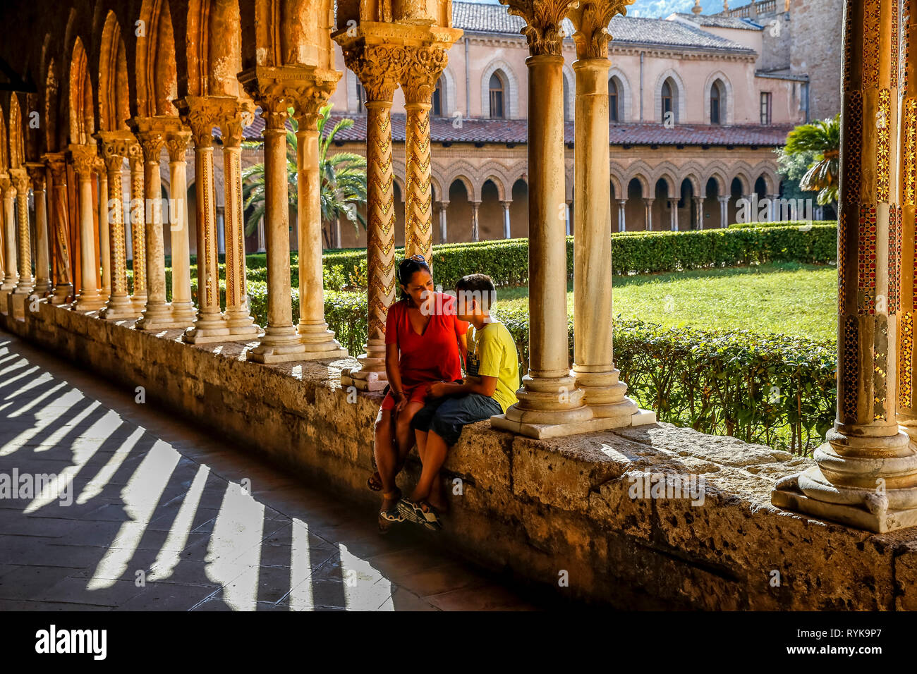 12-year-old boy sitting with his mother in the cloister of Monreale cathedral, Sicily (Italy). Stock Photo